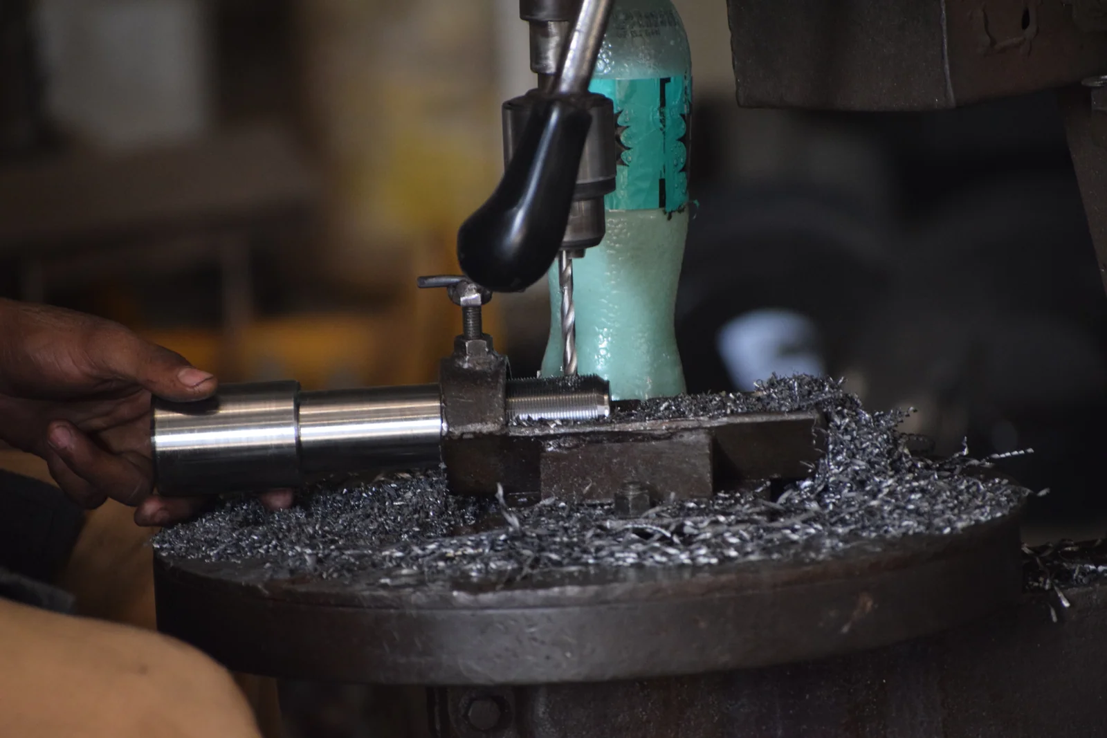 Steel shaft being turned on a lathe with metal swarf collecting below